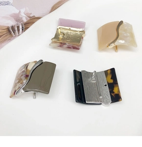 Flat lay of four resin hair clips featuring leopard print and marble textures for women