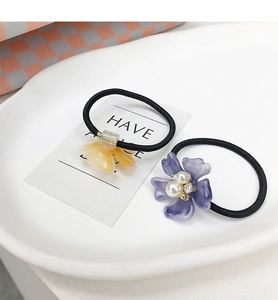 Detalle de gomas de pelo de flores amarillas y moradas con perlas en un plato de cerámica