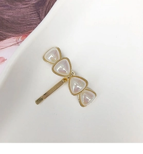 Detail of a golden metal hair hook with triangular pearlescent stones in a bow shape