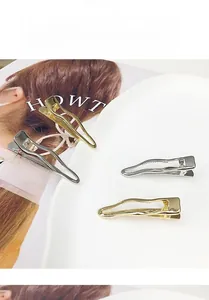 Detailed view of silver and gold wavy hair clips arranged on a white ceramic plate