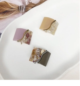 Close-up of three geometric leopard resin hair clips with elegant metal wave accents