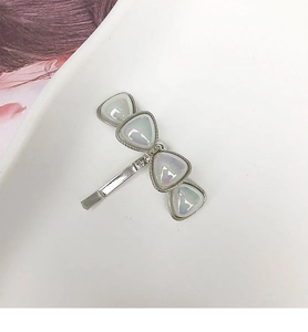Detailed macro shot of silver hair hook with four iridescent triangular resin charms