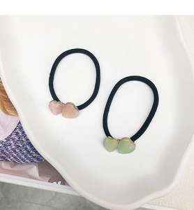 Détail de chouchous à perles en cœur rose et vert avec élastiques dans un plat décoratif