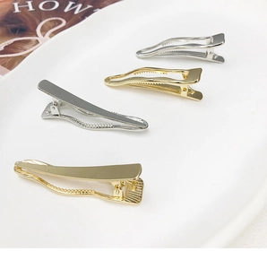 Close-up of wavy gold and silver metal hair clips displayed on a white ceramic plate