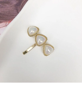 Macro detail of elegant hair hook featuring pearl-like triangular ornaments and gold borders