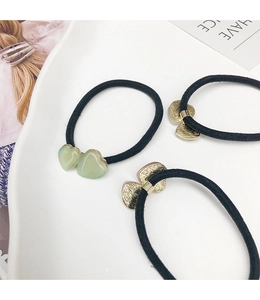 Vue détaillée de trois élastiques à cheveux avec pendentifs en forme de cœur en résine et métal