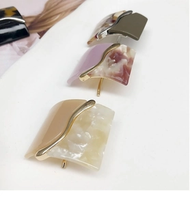 Detailed macro view of geometric acetate hair clips with marble texture and gold metal joints