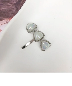 Detailed close-up of a minimalist silver hair clip with three iridescent opal-like stones