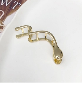 Détail d'une pince à cheveux dorée minimaliste avec un design incurvé irrégulier unique