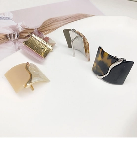 Detailed close-up of four leopard print resin hair pins in various colors on a ceramic tray