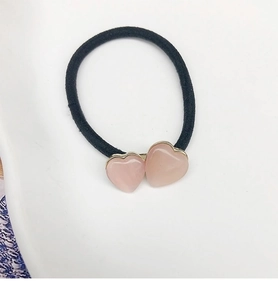 Détail d'un élastique à cheveux cœur rose avec bords dorés et bande noire robuste
