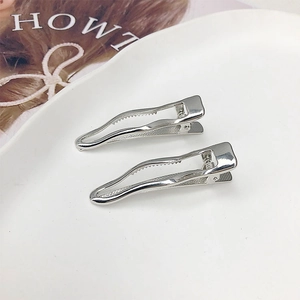 Silver metal wavy hairpins in a white ceramic dish with magazine backdrop props