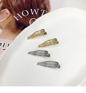 Close-up of set of 4 liquid metal wave hair clips in gold and silver on ceramic plate