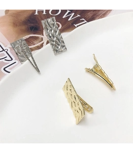 Détail des barrettes à cheveux dorées et argentées avec texture en métal martelé chic