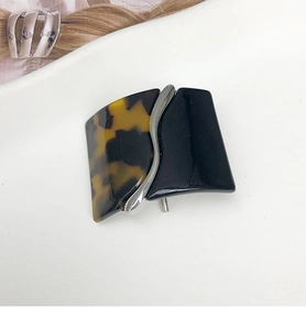 Macro view of the two-tone tortoiseshell and black acetate hair clip with silver wavy line