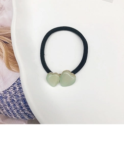 Gros plan d'un élastique à cheveux noir avec cœurs verts sur une assiette en céramique