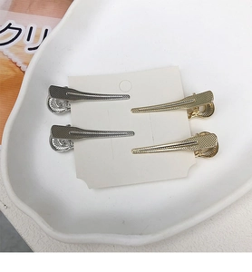 Dettaglio di quattro fermagli per capelli in metallo oro e argento con trama zigrinata