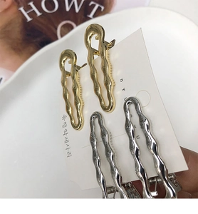 Dettaglio macro di fermagli per capelli a onda irregolare in metallo oro e argento