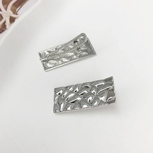 Détail de barrettes rectangulaires en métal argenté avec texture géométrique martelée chic