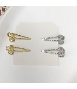 Detailansicht von vier goldenen und silbernen hohlen Dreieck-Haarspangen auf einer Karte