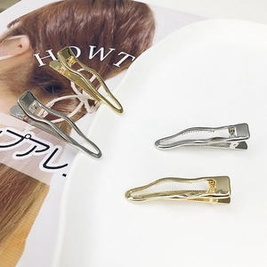Minimalist wavy hollow metal hair clips in gold and silver finish on ceramic plate
