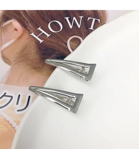 Dettaglio di due fermagli per capelli a triangolo argento con design geometrico in metallo