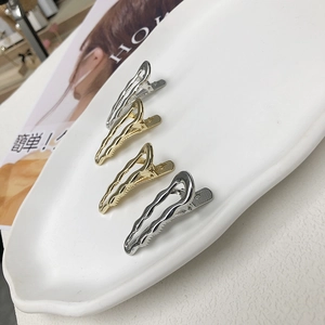 Set di fermagli per capelli ondulati oro e argento su un vassoio di ceramica