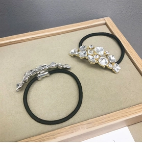 Dettaglio di grappoli di strass scintillanti su elastici neri ad alta elasticità in oro e argento