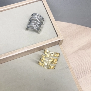 Minimalist wavy metal hair hooks in gold and silver finish on a display tray