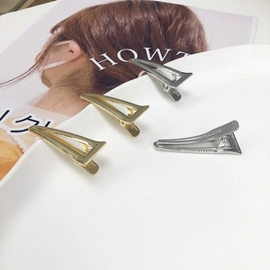 Set di fermagli per capelli triangolari in metallo oro e argento su un piatto bianco