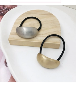Detail of high-elasticity black hair ties with gold and silver matte metal accents