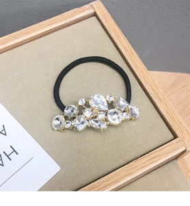 Dettaglio dell'elastico per capelli nero con strass geometrici su base dorata