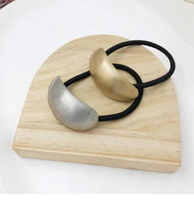 Detailed shot of matte gold and silver crescent charms on high elasticity hair ties