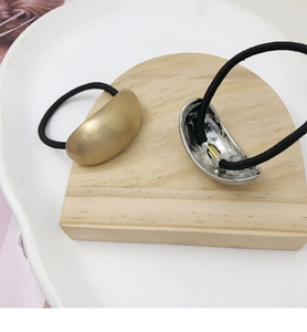Detail of matte gold and textured silver metal hair ties on high-elastic black bands