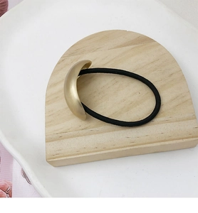 Close-up of a high-elastic black hair tie with a matte gold crescent metal decorative piece