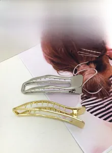 Macro detail of wave-shaped gold and silver metallic hair claws for thick hair styling