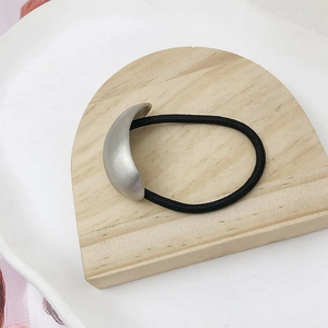 Detail of high-elastic black hair tie featuring a brushed silver crescent metal charm