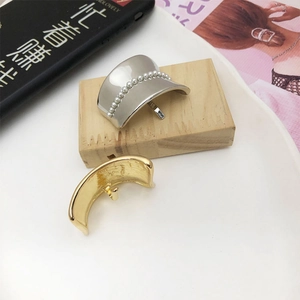 Detail of silver pearl and gold minimalist metal hair hooks on a wooden block