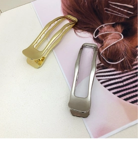 Detail of gold and silver rectangular metal hair claws with wavy edges and hollow design