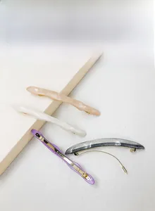 Detailed macro view of four marble patterned hair clips with golden metal spring fasteners