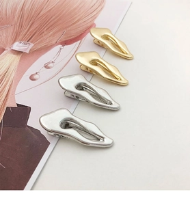 Detail of irregular liquid-wave metal hair clips in gold and silver finishes