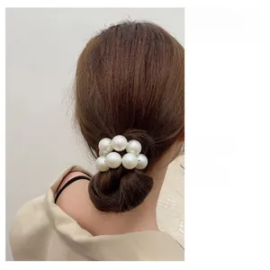 Detail view of model wearing a white pearl hair tie on a neat high bun hairstyle