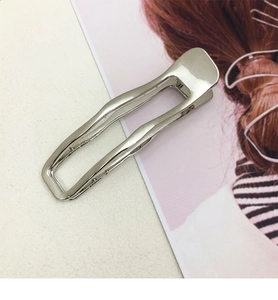 Detail of silver wavy metal hair clip with polished alloy finish and minimalist design