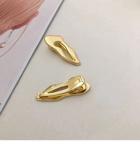 Detailed view of two irregular gold metallic hair clips with anti-slip duckbill grip design
