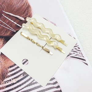 Macro shot of wavy resin hair clips and golden barrettes on a white display card