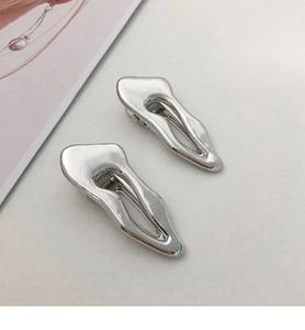 Detailed macro view of liquid metal silver hair clips with minimalist irregular design