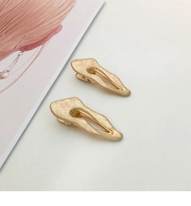 Detail of golden irregular hair clips with matte hammered texture and organic design