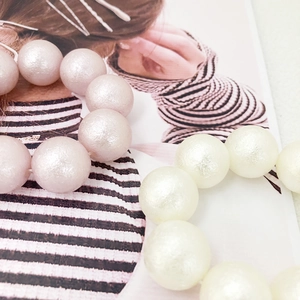 Macro shot of faux pearl elastic hair ties in pastel pink and ivory white colors