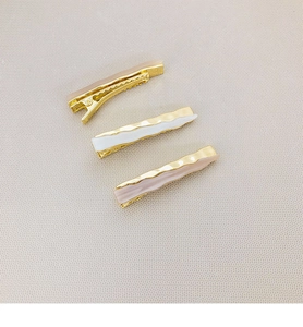 Three-piece hair clip set in champagne gold and pearl white on leather background