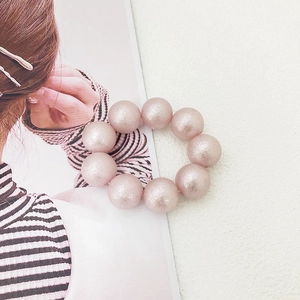 Macro shot of light pink large imitation pearls hair tie with frosted pearlescent finish